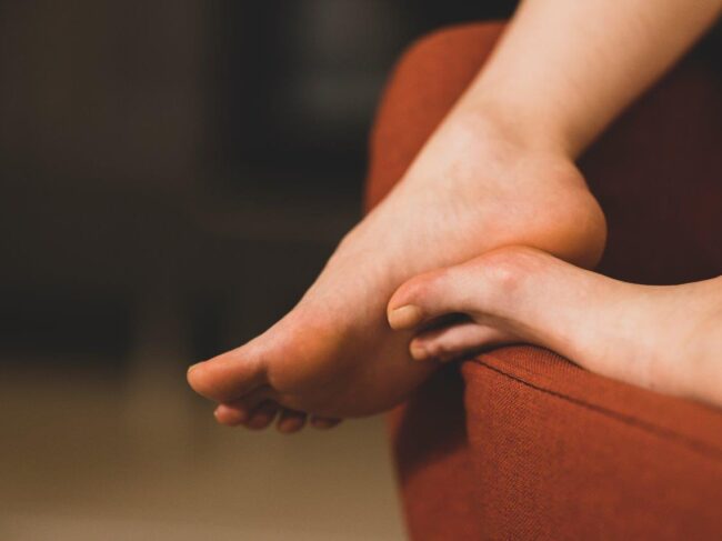 Person pressing painful foot arch