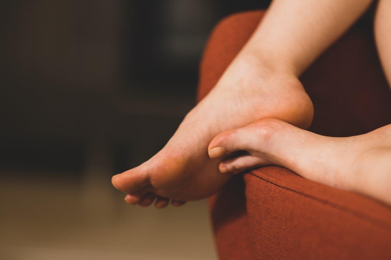 Person pressing painful foot arch