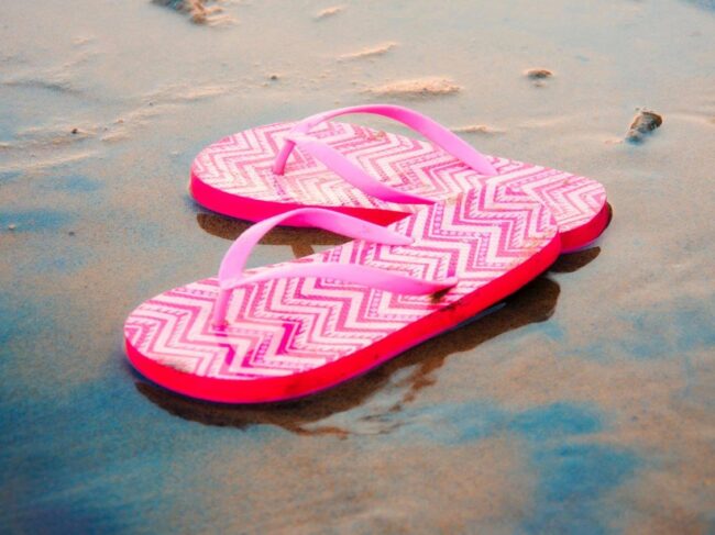 pair of pink flip flops on a beach